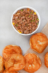 South African vetkoek, deep fried savory dough filled with saucy savory mince on mottled grey background with copy space

