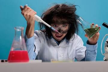 Foolish silly female lab worker with pipette and glass jar mixing toxic chemical compounds to...