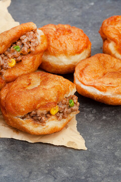 South African vetkoek, deep fried savory dough filled with saucy savory mince on mottled grey background with copy space


