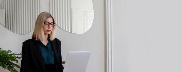 
Portrait of a young european woman in business clothes with a laptop at the workplace with a phone in her hands with space for copyspace.