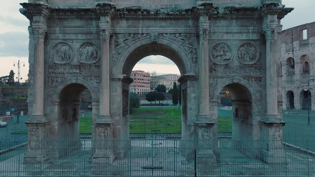 Aerial drone view through the Arco di Costantino arch in front of the Colosseum, in Rome, Italy