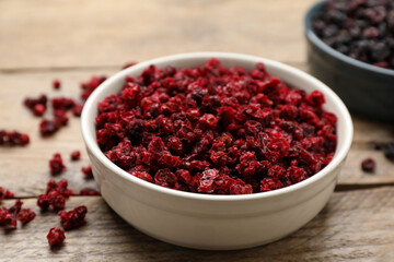 Bowl of dried red currant berries on wooden table, closeup