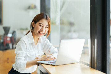 Beautiful cute asian young businesswoman in the cafe, using computer laptop.