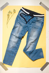 blue women's jeans lie on yellow background