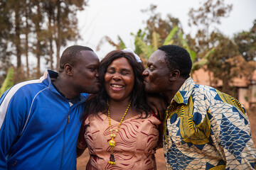 Happy African family, son and husband give a kiss to the mother in the middle