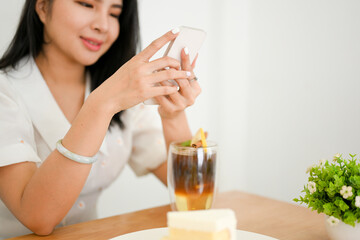Attractive Asian woman relaxes in cafe, using her smartphone