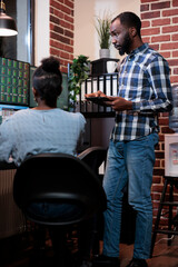 Insurance company professional agent in workspace reviewing real time stock market data. Financial advisors analyzing buy and sell price ranges while sitting at multi monitor workstation at night.