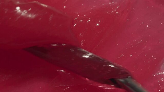 Wax cream cosmetic background video. Pink sticky balm, sweet toothpaste for children, gel. Red tooth paste texture spreading by spatula footage. 