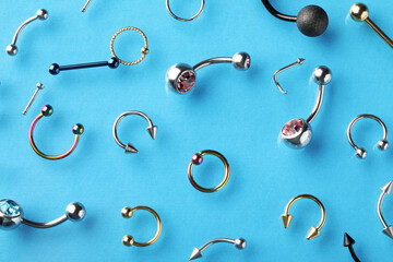 Stylish piercing jewelry on light blue background, flat lay