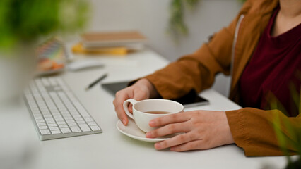 Businesswoman having a cup of hot tea at the office desk.