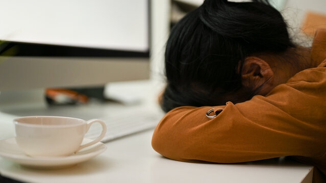 Tired female office worker laid her head down on the table. Exhausted, Frustrated.