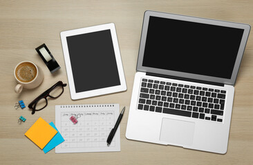 Modern gadgets, cup of coffee and office stationery on wooden table, flat lay. Distance learning
