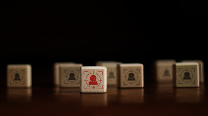 The red man target icon stands out on the wooden block at the front and there is a wooden block with a blurred black man icon on the back. business growth idea business leadership on dark background