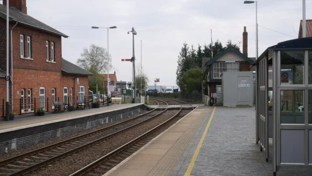 A double decker bus crossing the rail tracks at an old village railway station in England