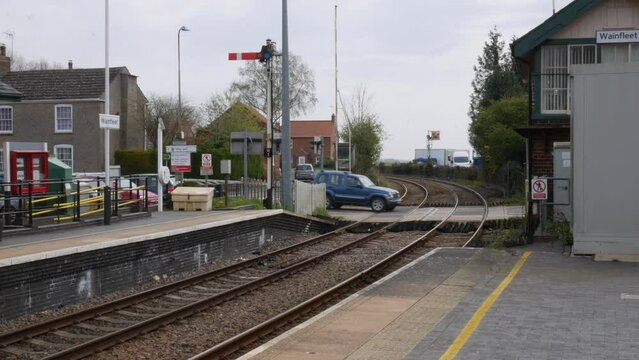 Cars crossing the rail tracks at an old village railway station in England