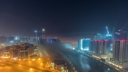 Buildings are covered in thick layer of fog in Business Bay night timelapse.