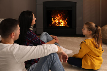 Happy family spending time together near fireplace at home