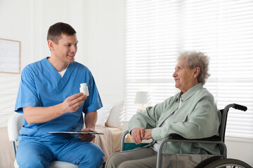 Caregiver giving medication to senior woman indoors. Home health care service