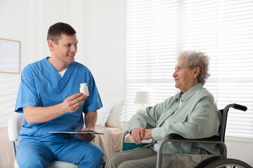 Obraz premium Caregiver giving medication to senior woman indoors. Home health care service