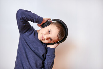 A handsome boy listens to music in headphones with pleasure and a smile.