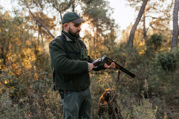 Hunter opening his hunting shotgun and watching cartridge in nature