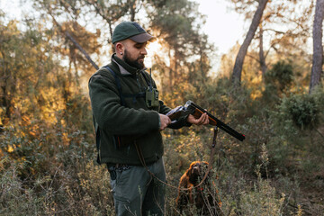 Fototapeta premium Hunter opening his hunting shotgun and watching cartridge in nature