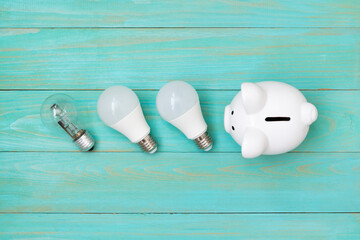 Piggy bank and  light bulbs on blue wooden background