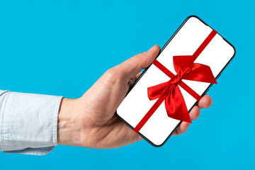 Smartphone in a man's hand tied with a red ribbon and a bow