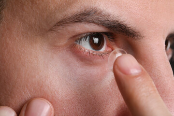 Closeup view of man putting contact lens in his eye