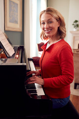 Portrait Of Mature Woman At Home Enjoying Learning To Play Piano
