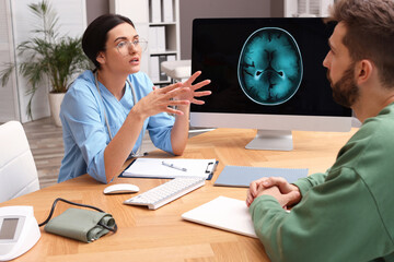 Neurologist consulting patient at table in clinic