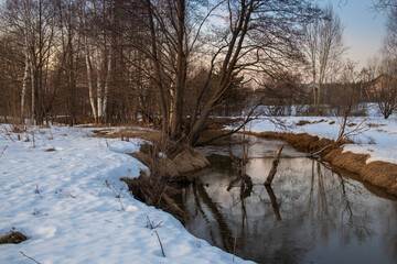 Evening spring landscape. Awakening of nature after winter. Charming evening landscape in early spring. Melting ice and snow.