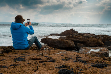 Male tourist standing on a rough stone coast. Aran island, county Galway, Ireland. Blue cloudy sky in the background. Travel and tourism concept. Beautiful Irish landscape in the background.