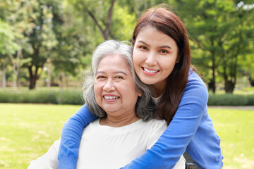 Elderly mother and daughter smiling happily in the park in the morning. Family concept. Health care...