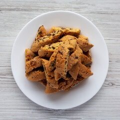 Homemade Italian Cantuccini with Chocolate on a White Plate on a white wooden background, top view. Crispy Chocolate Cookies. Flat lay, overhead, from above.