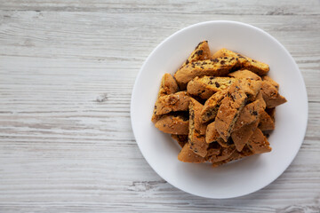 Homemade Italian Cantuccini with Chocolate on a White Plate on a white wooden surface, top view. Crispy Chocolate Cookies. Flat lay, overhead, from above. Copy space.