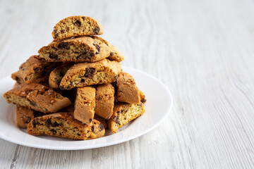 Homemade Italian Cantuccini with Chocolate on a White Plate on a white wooden surface, side view....