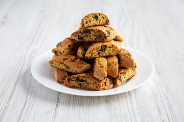 Homemade Italian Cantuccini with Chocolate on a White Plate on a white wooden surface, side view. Crispy Chocolate Cookies.