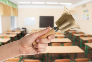 Woman with school bell in empty classroom, closeup
