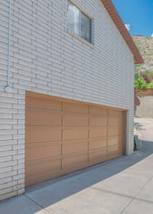 Vertical White puffy clouds Uphill curved driveway beside the garage with sliding window and white texture bricks wall