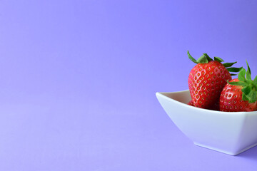 Strawberry in a bowl, mauve background.