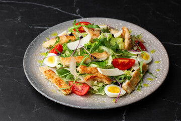 A Caesar salad with grilled chicken breasts, lettuce, croutons, eggs, cherry tomatoes, dressed with Parmesan cheese and sauce.