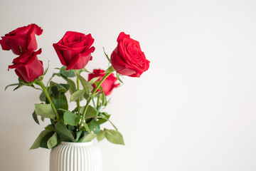 Bouquet of red roses in a white ceramic vase.