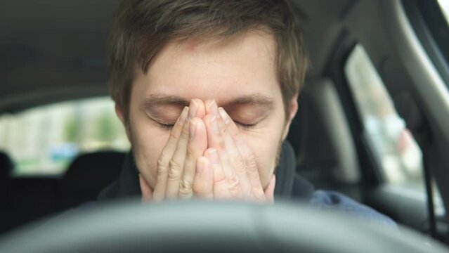 Depressed young man driver sitting in his car, feeling emotional burnout. Mental health concept.