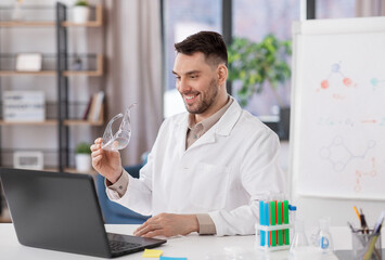 distance education, school and science concept - happy smiling male chemistry teacher with laptop computer and goggles having online class at home office