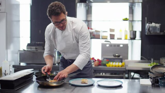 Professional male chef in uniform preparing orders in restaurant kitchen