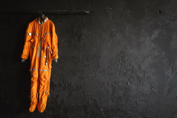 Concept of space suit hanging on the black wall background with copy space. © Dmitriy