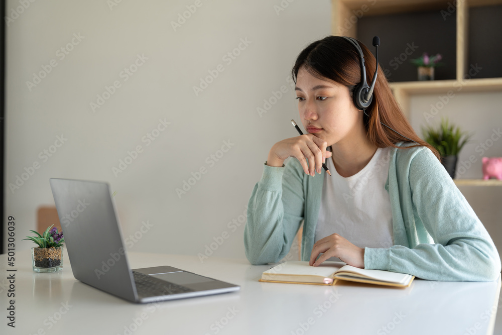 Wall mural Happy young woman studying online, watching webinar, podcast on laptop. E-learning concept