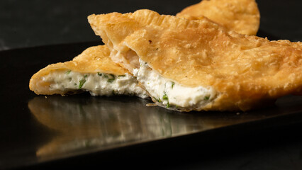 Uzbek eastern Tatar cuisine, cheburek with suluguni cheese a black board. Cheburek - fried pie. Traditional dish of Turkish and mongolian.