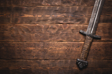 Knight sword on the wooden flat lay table background with copy space.